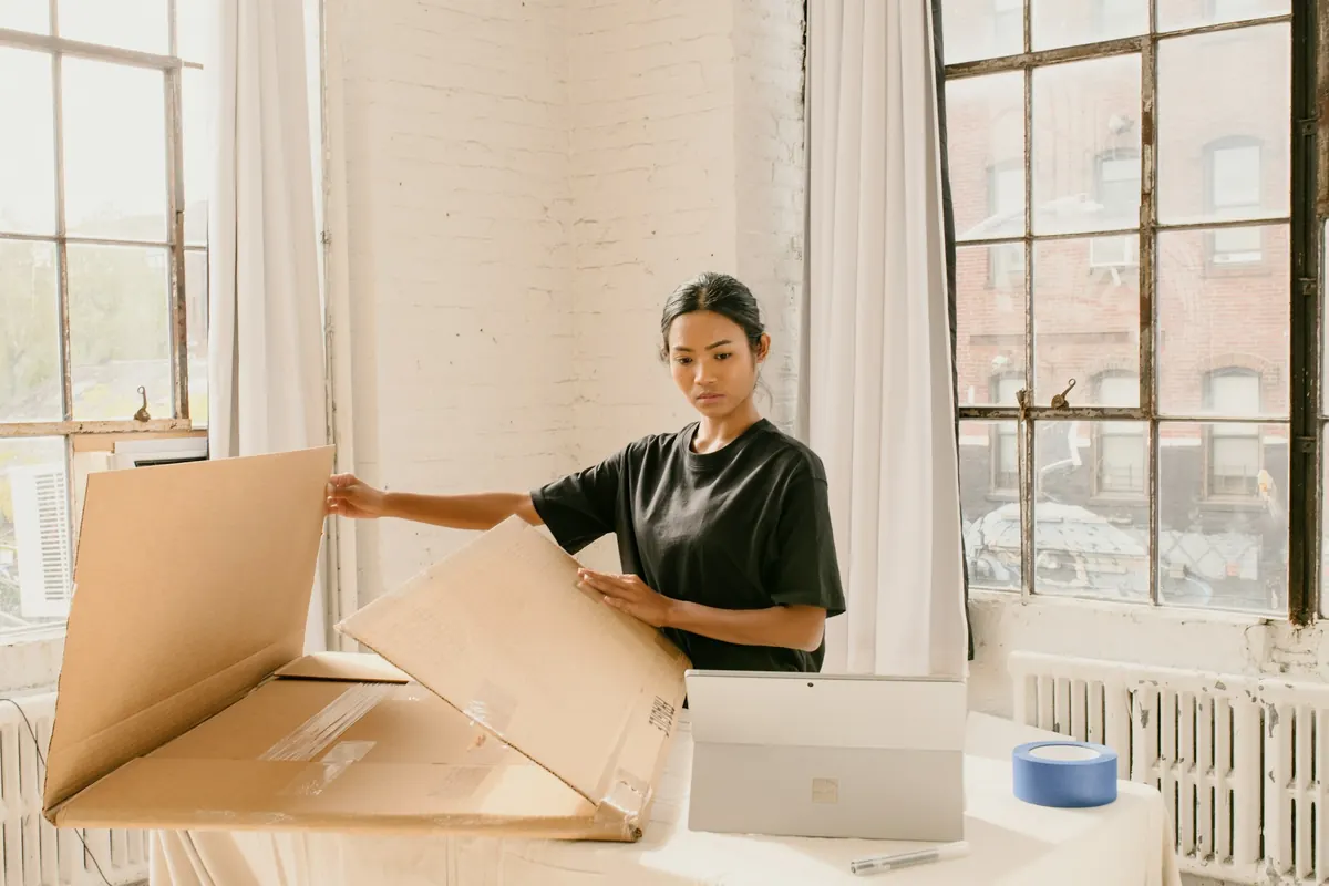 Une femme assemble un carton d'expédition dans un atelier lumineux
