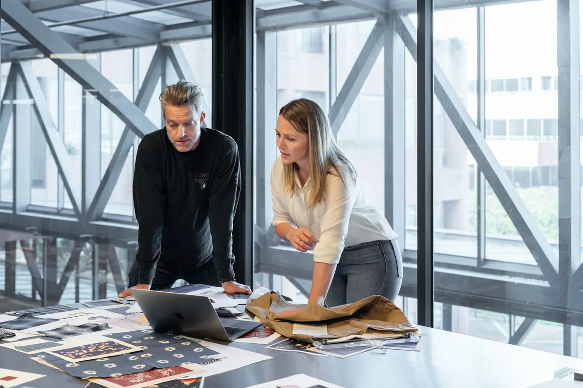 Un homme et une femme penchés sur une table de travail couverte de documents