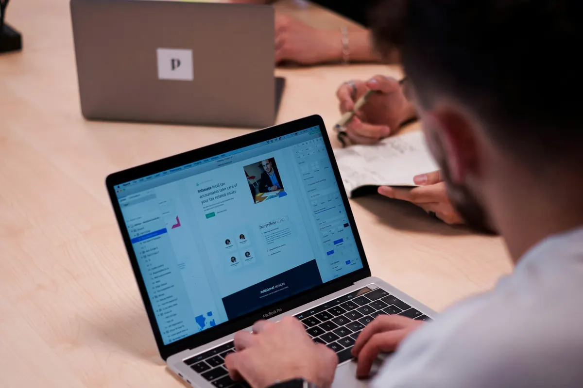 Un homme consulte un site sur son ordinateur portable et prend des notes