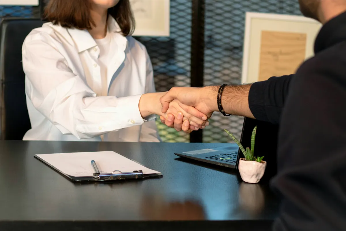 Poignée de main au-dessus d'un bureau, un document posé sur la table
