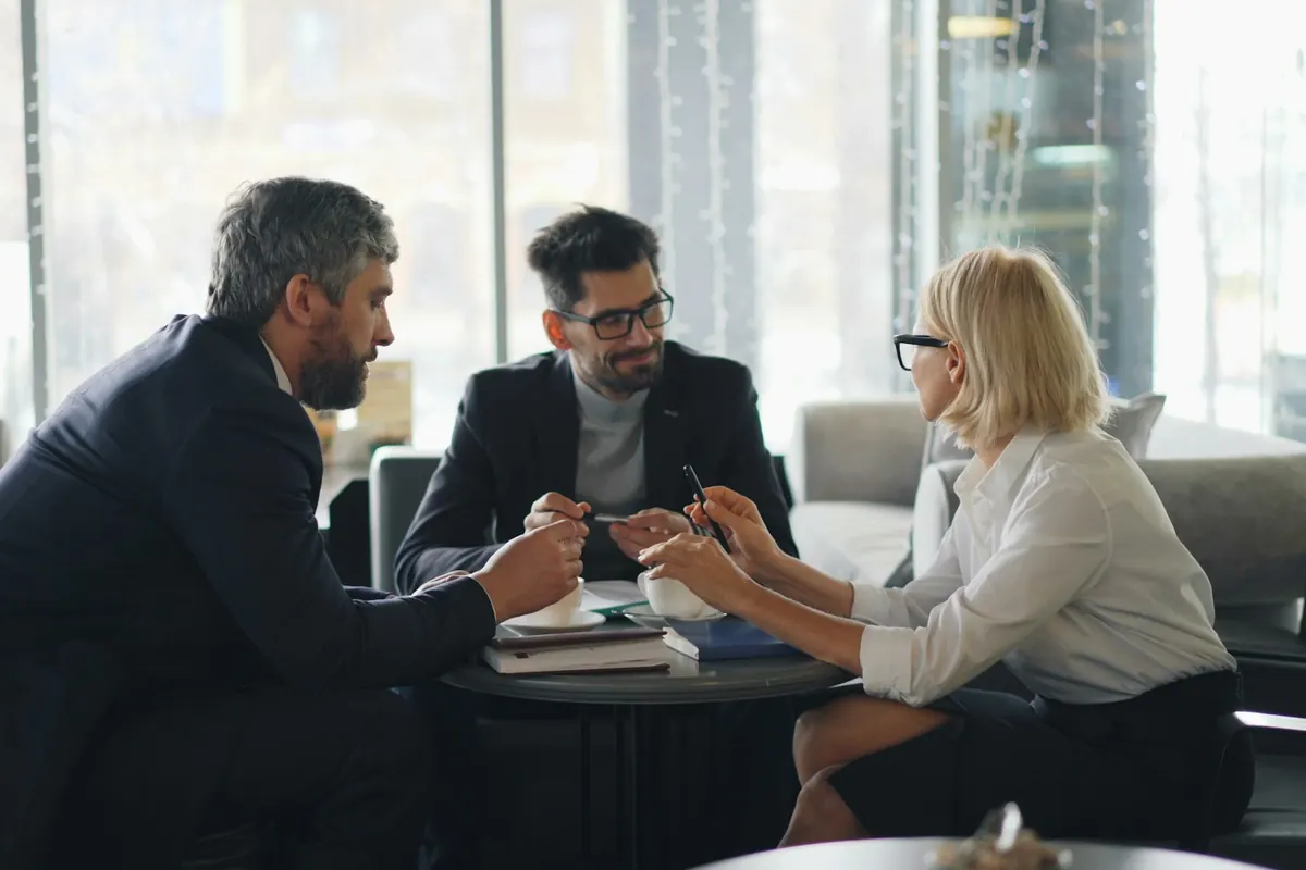 Trois personnes échangent autour d'une table lors d'un rendez-vous professionnel