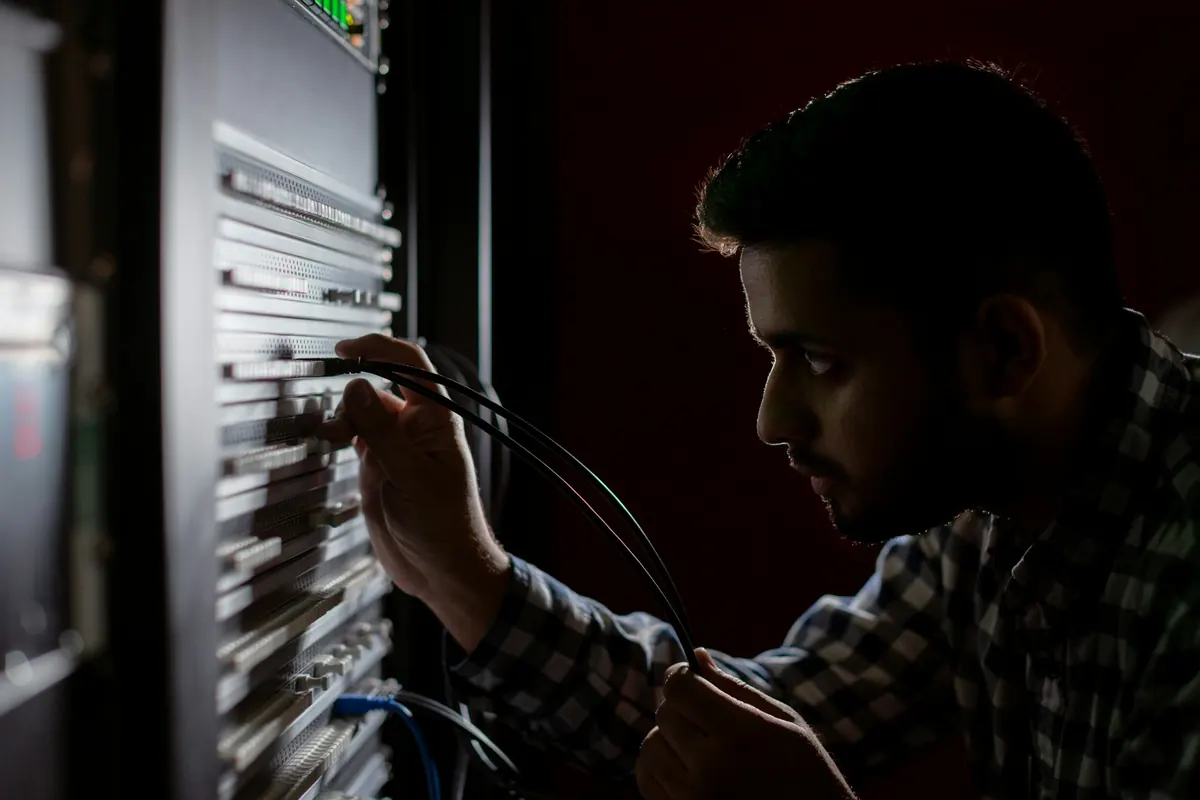 Un technicien branche des câbles réseau dans une baie informatique