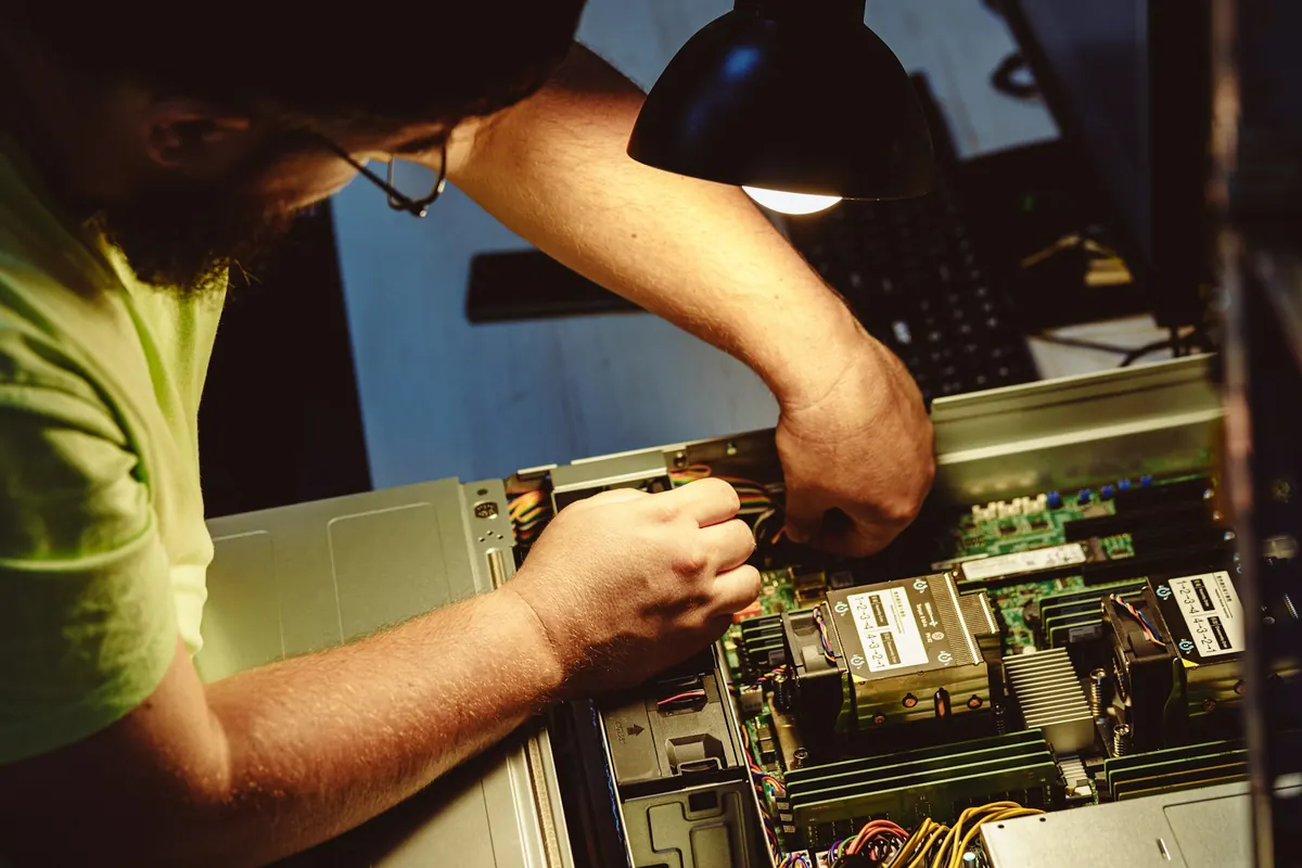 Un technicien intervient à la lampe sur les composants d'un ordinateur